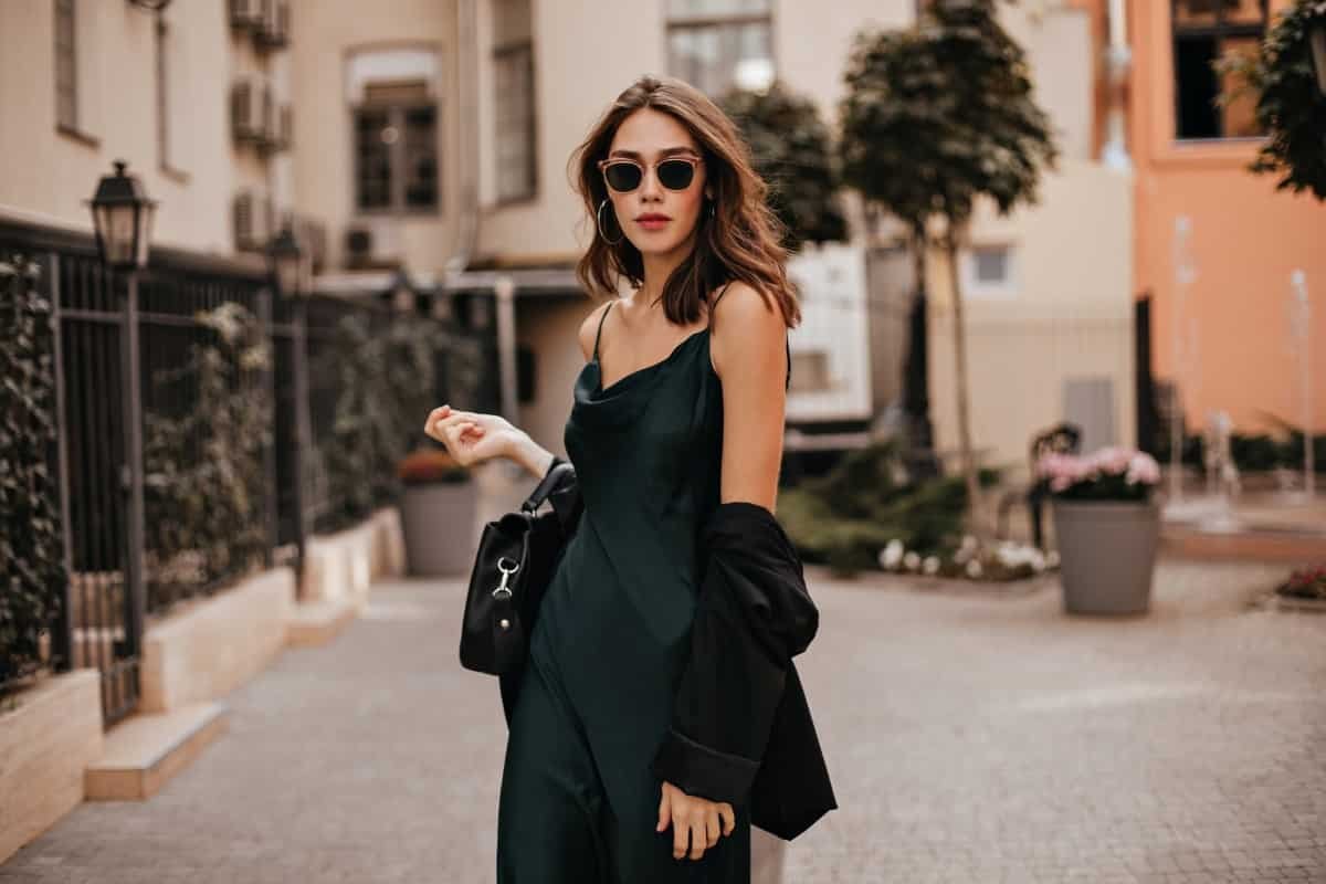 Home Fashionable Pale Brunette Long Green Dress Black Jacket Sunglasses Standing Street During Daytime Against Wall Light City Building 1